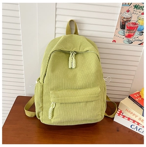 Detail of light green corduroy backpack showing textured fabric and zipper with cord pull