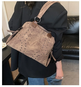 Detail of vintage brown suede tote featuring silver studs in a V-pattern and ring hardware
