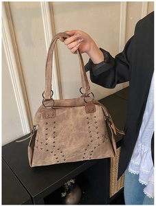 Detail of vintage brown suede tote with dark metal rivets and long shoulder straps