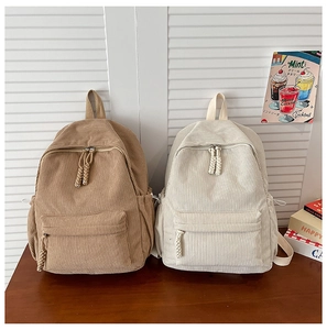 Detail of corduroy backpacks in khaki and beige featuring unique woven zipper pulls