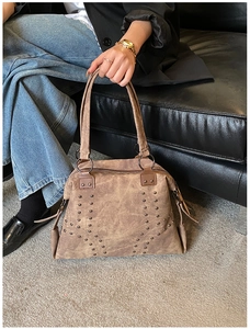 Detailed side view of vintage brown tote bag with metal rivets and sturdy leather handle