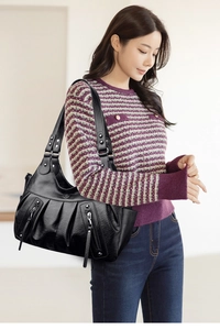 Close-up of black pleated tote bag with vertical zipper detail shown on a female model