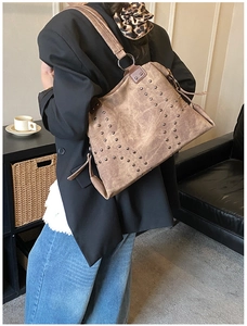 Detailed side view of vintage brown tote bag with metal rivets and shoulder strap