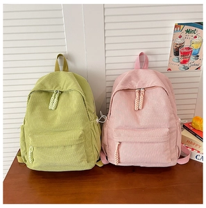 Detail of corduroy backpacks in mint green and soft pink colors with woven rope zippers