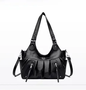 Front detail of black leather tote bag with pleated design and silver metal zippers