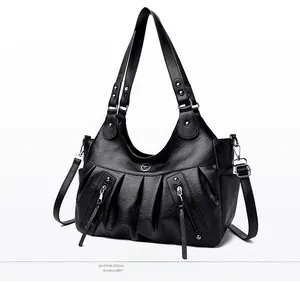 Detailed view of black pleated tote bag with silver zippers, tassels and metal logo