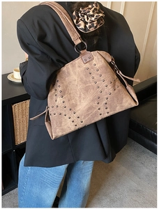 Close-up of retro brown shoulder bag with metallic rivets and vintage faux leather texture