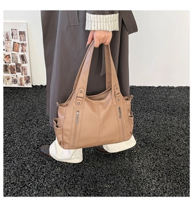Detail of tan tote bag with decorative silver zippers and spacious side pockets