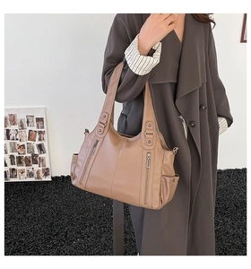 Close-up of tan pebble leather tote bag with functional vertical zippers and side pockets
