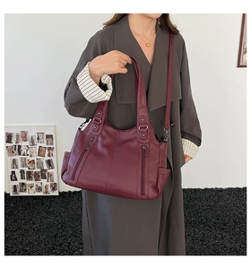 Detail of burgundy pebbled leather tote showing side pocket and adjustable shoulder strap