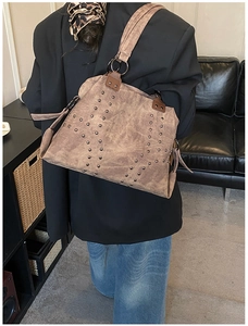 Detail of a vintage tote bag with metal studs and wide shoulder strap in taupe finish