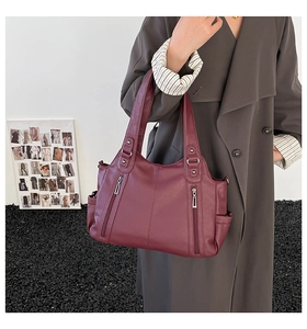 Woman modeling a wine red leather tote bag with functional side zippers and large capacity