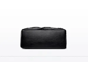 Detail view of the wide base and pleated texture of this black leather tote bag