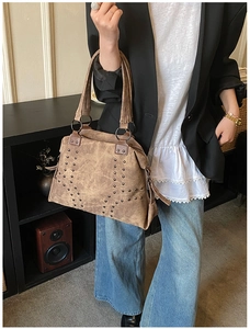 Detail of vintage brown tote bag with retro metallic rivets and textured leather finish