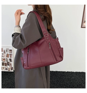 Detail view of large burgundy tote bag with pebble leather texture and side zipper pockets