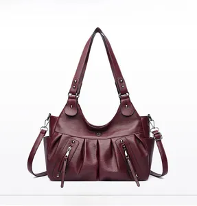 Detail of vintage pleated texture and silver zippers on a burgundy leather tote bag