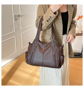 Detail of dark brown leather tote bag showing vertical zippers and pebble grain texture