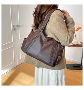Detail of dark brown lychee leather tote bag showing grainy texture and front zipper pocket