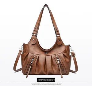 Detailed view of brown faux leather texture with pleated design and tassel zipper on tote bag