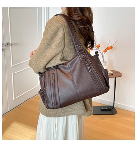 Detail of dark brown leather tote bag with vertical zippers and soft lychee texture