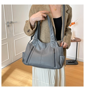 Close-up of grey soft faux leather tote bag with vertical zippers and reinforced handles