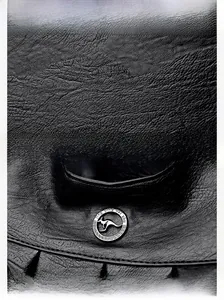 Macro shot of durable black litchi grain leather and a round kangaroo metal logo detail