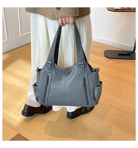 Detail view of grey litchi leather tote bag with functional vertical zippers and side pockets