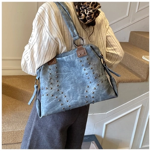 Detail of blue tote bag with metallic studs, tassels, and vintage washed leather texture