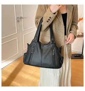 Detail of black pebbled leather tote bag with functional silver zippers and reinforced handles
