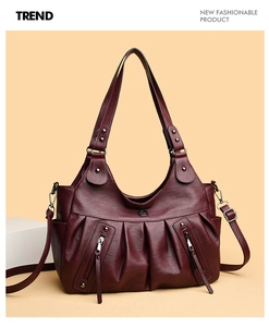 Macro shot of burgundy tote bag with pleated leather texture and vertical zipper pockets