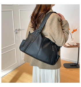 Close-up of black leather tote bag with vertical zipper details on model's shoulder