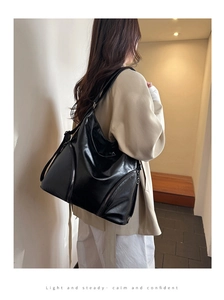 Detail of black large capacity leather tote bag with side zipper and shoulder strap