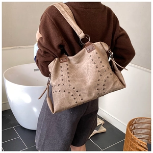 Detail of vintage studded tote bag in khaki faux suede with metallic rivet accents