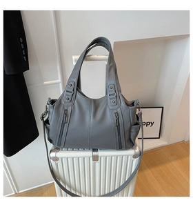 Detail of grey PU leather tote bag with lychee texture on a white suitcase