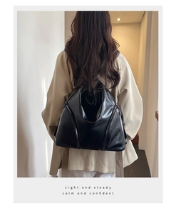Rear view of a model wearing the black faux leather backpack with side zipper details