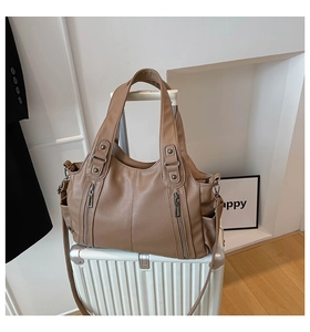 Brown litchi grain tote bag with dual zippers placed on a white suitcase for travel
