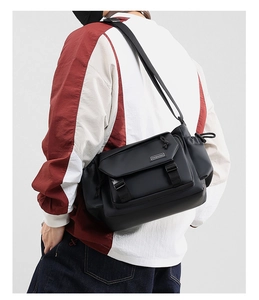 Close-up of black messenger bag featuring buckle closure and Fashion brand label