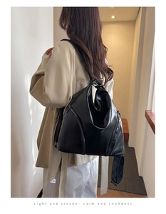 Detail view of large black leather backpack showing side metal zipper and soft texture