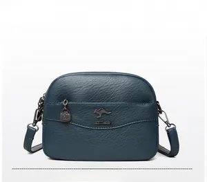Dettaglio della borsa a tracolla in pelle blu con trama fine e logo a canguro in metallo