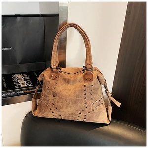 Detail of vintage brown tote bag with metal studs and textured matte leather finish