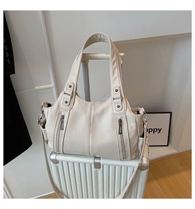Detail of cream lychee leather tote bag featuring dual front zipper pockets and silver hardware
