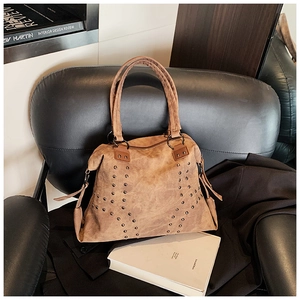 Detail of vintage brown tote bag featuring decorative metal studs and premium suede texture