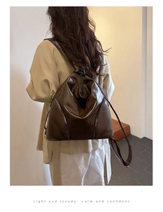 Detail view of large dark brown leather backpack showing side zipper and triangle shape