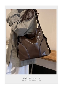 Detailed shot of dark brown glossy leather tote bag with stylish diagonal zippers