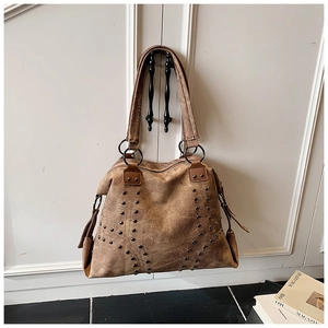 Detail of vintage brown tote bag featuring metallic rivets and retro leather texture