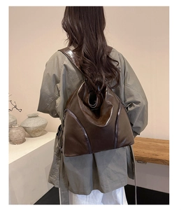 Detailed view of the dark brown leather backpack being worn on the model's back