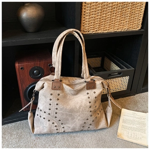 Close-up of vintage tote bag with bronze metal studs on brown matte textured leather