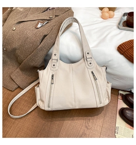 Detail view of large beige tote bag with pebbled leather texture and dual zip pockets