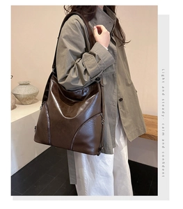 Detail of dark brown leather backpack with round metal logo charm and zipper pockets