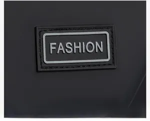 Macro shot of rubber 'FASHION' label with precise stitching on black messenger bag